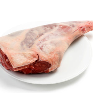 a raw leg of lamb against a white background